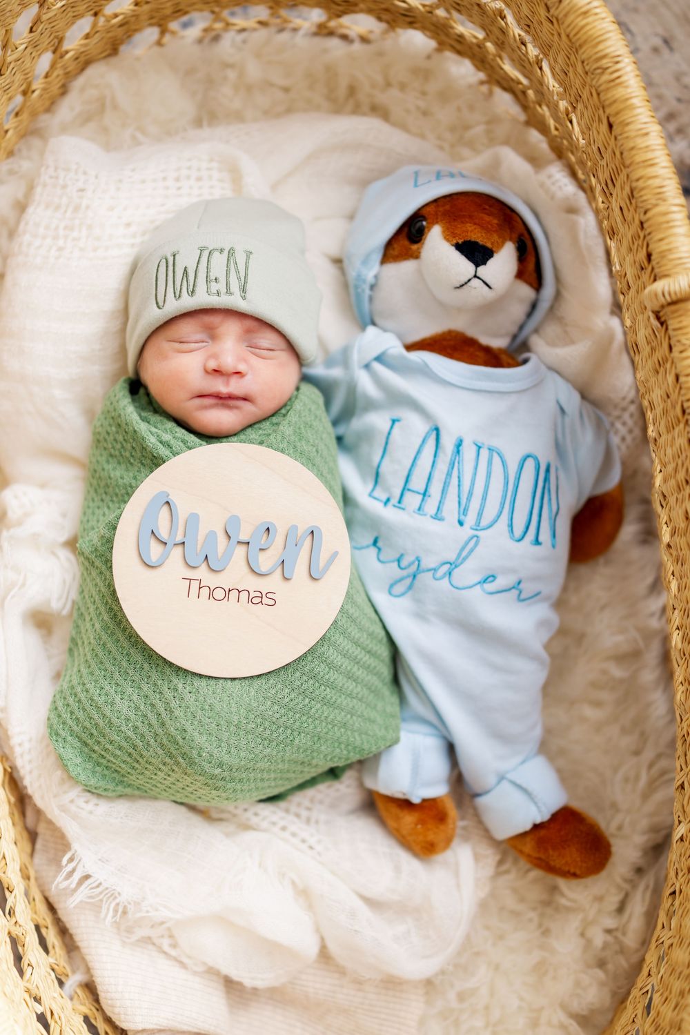 Newborn photography in woven basket with mint green swaddle and plush toy accessories.