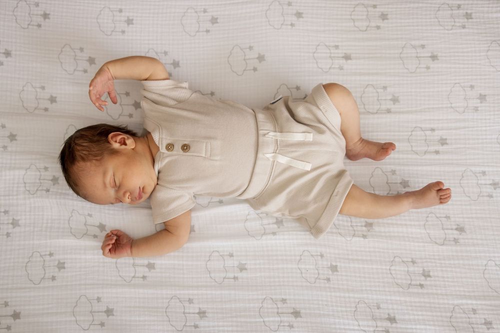 A sleeping baby lying on white bedding in various positions showing different angles of peaceful rest.