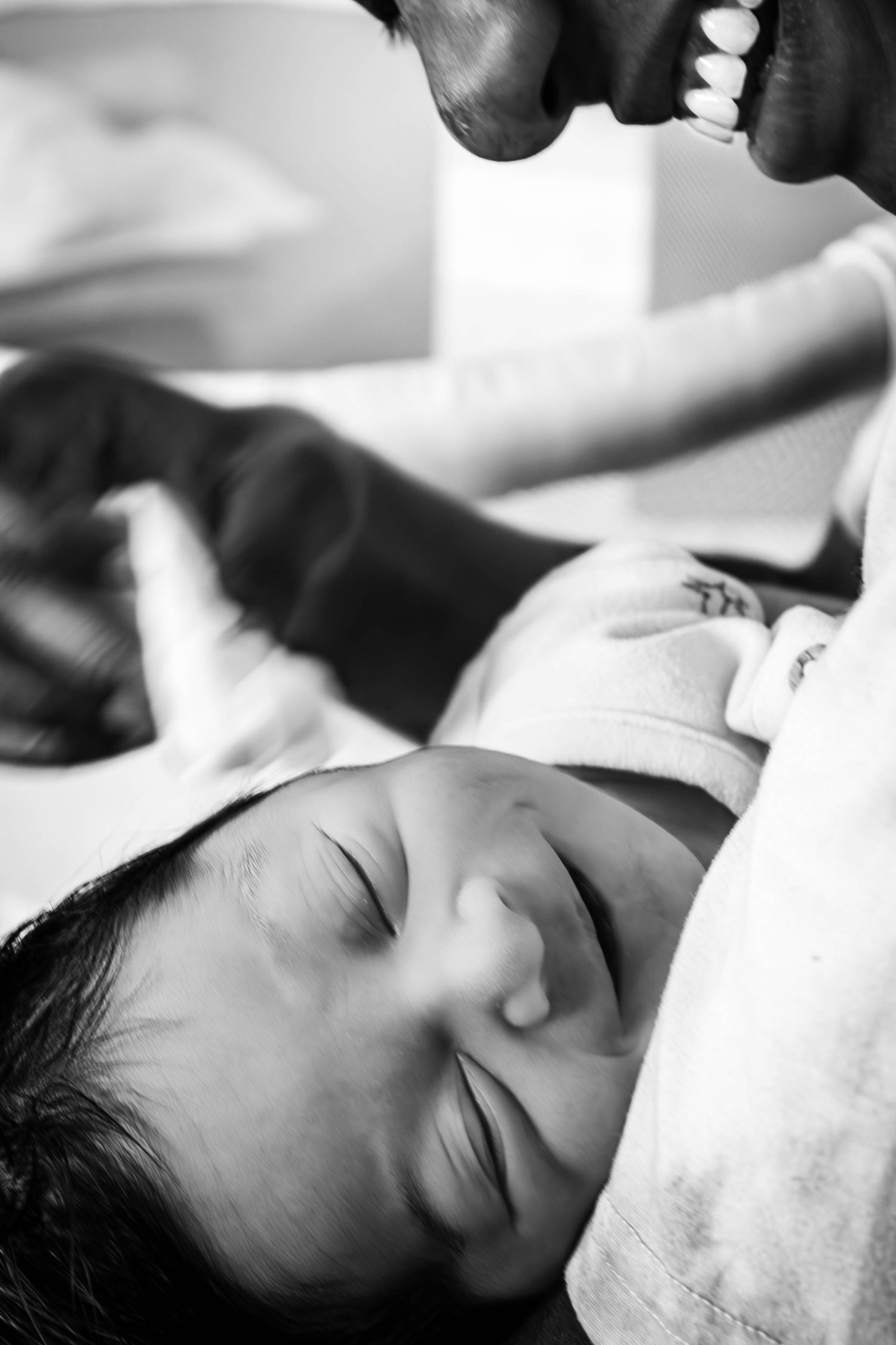 A sleeping baby with a soft smile in black and white photograph with soft lighting and shallow depth of field.