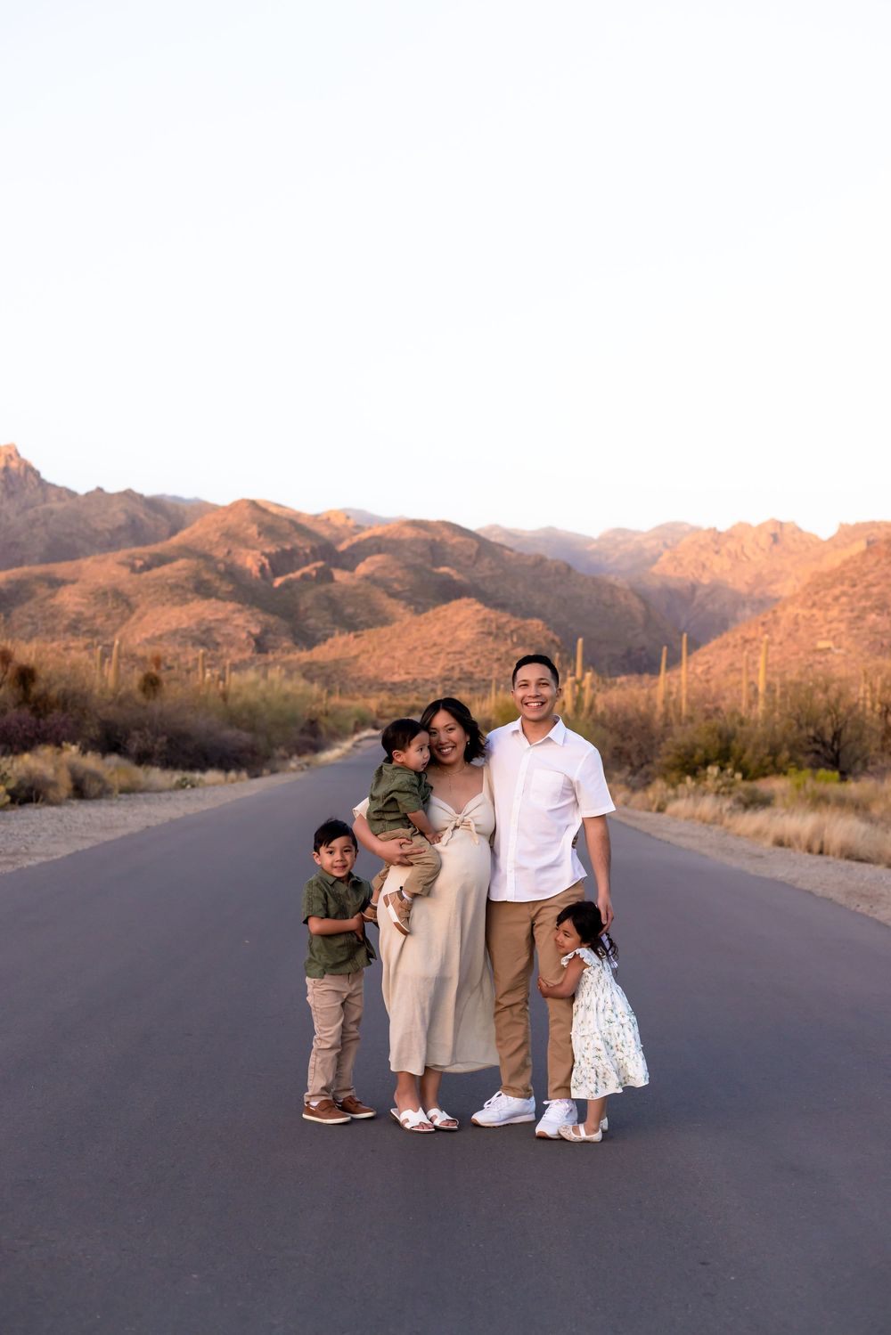 Family portrait session on desert road with mountains during golden hour.