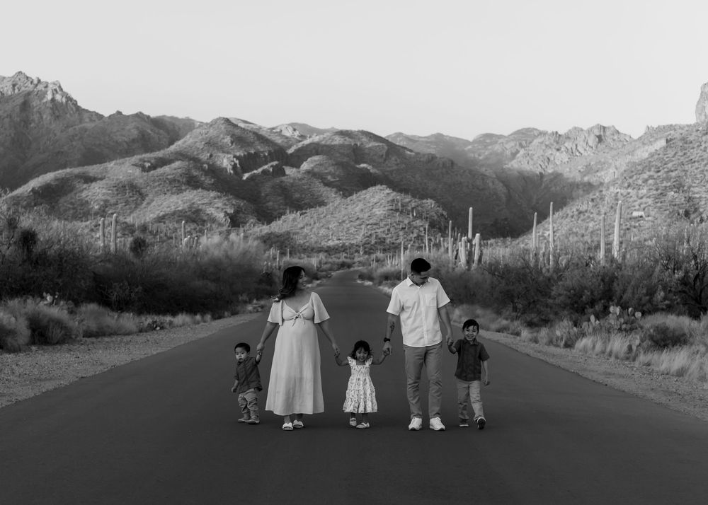 Family silhouettes against desert mountain landscape during sunset photoshoot.