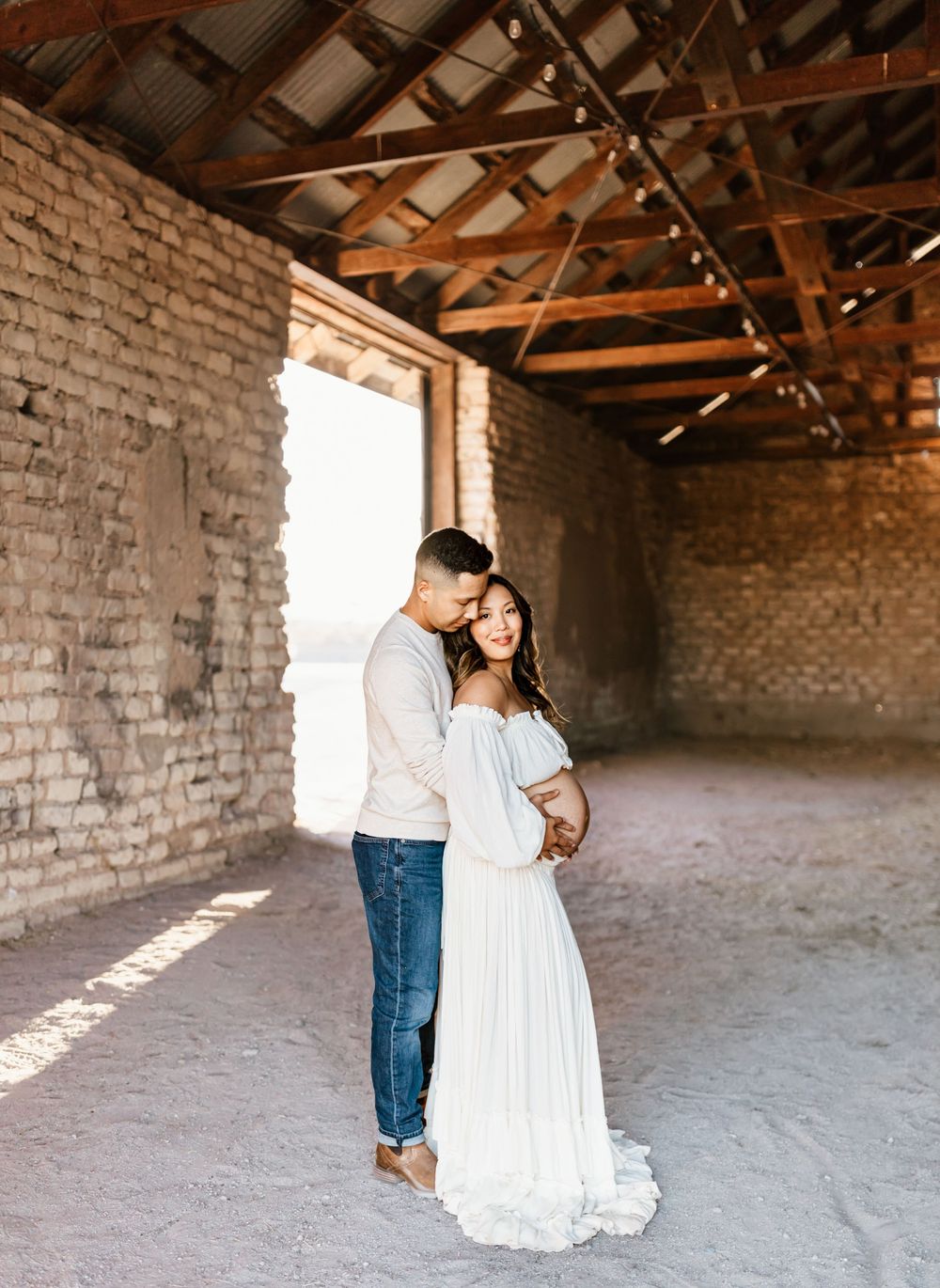 Romantic couple photos in rustic brick building with natural light streaming through.