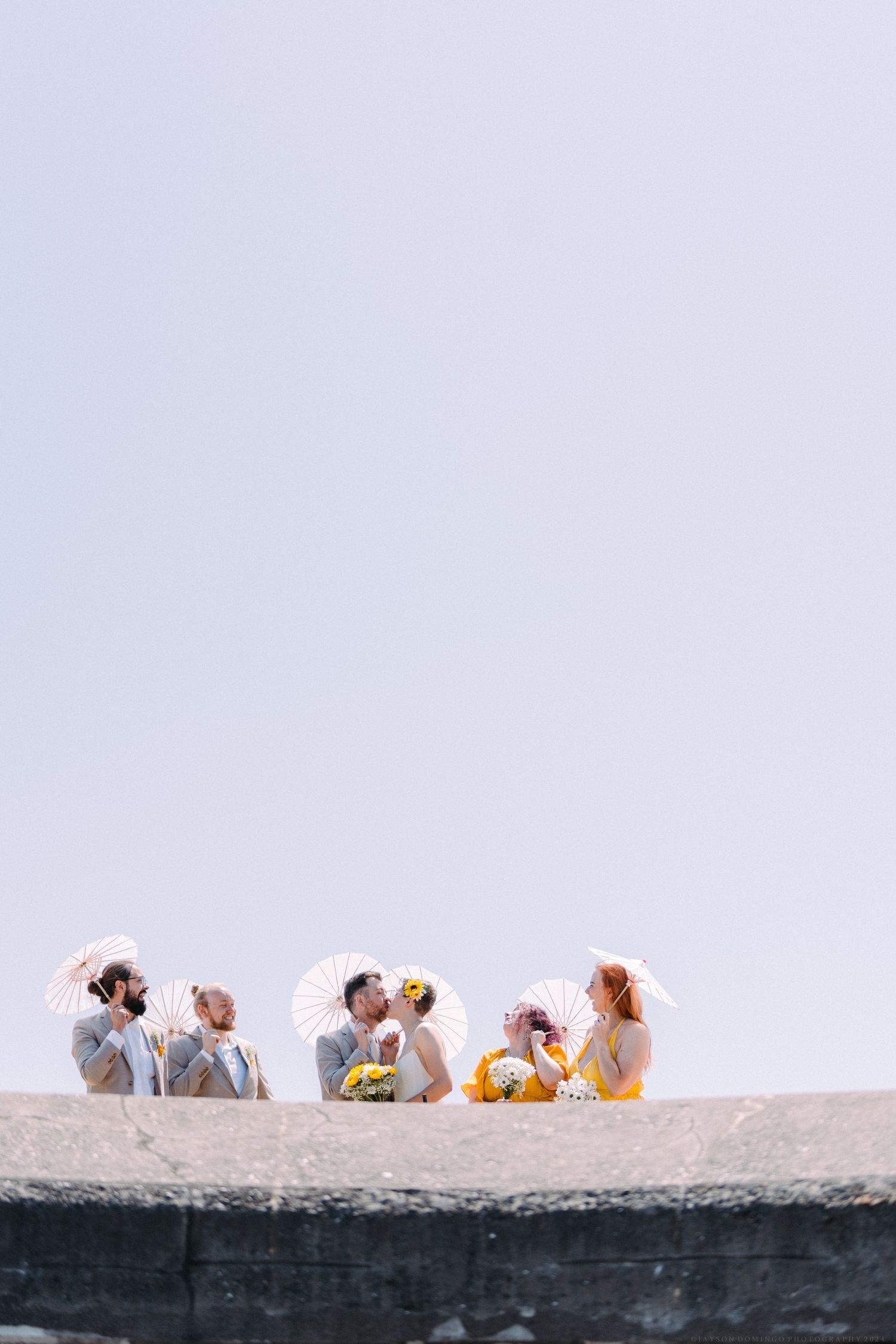 Group seated together on stone ledge against light background.