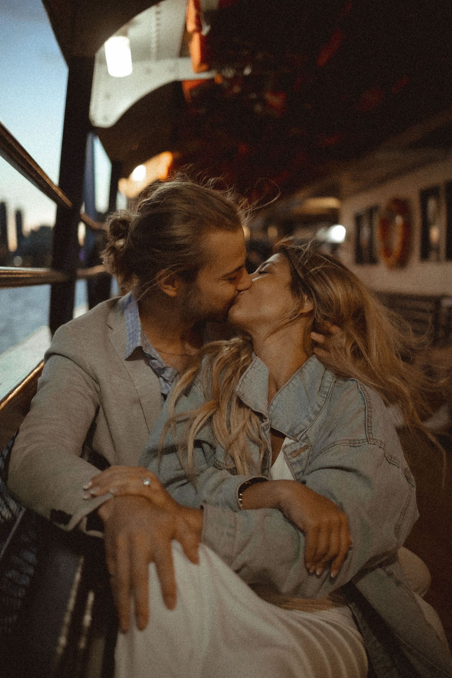A romantic golden hour kiss shared on a boat with warm sunset lighting.