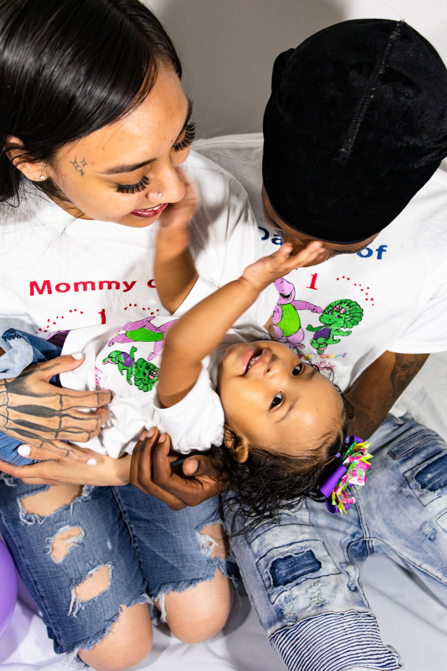 Playful family moment captured on white background with matching t-shirts.