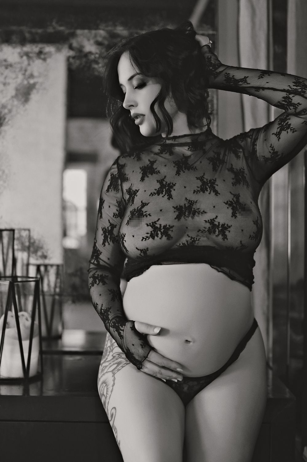 Maternity portrait featuring black lace top and natural window lighting.