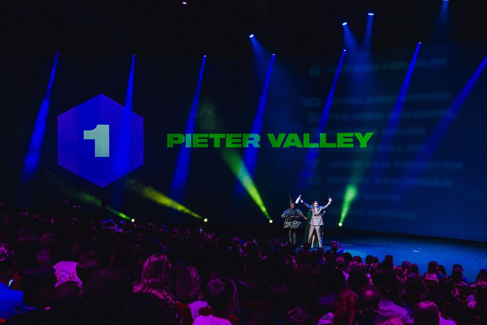 A performer stands on stage with dramatic blue and green lighting effects during a concert performance.