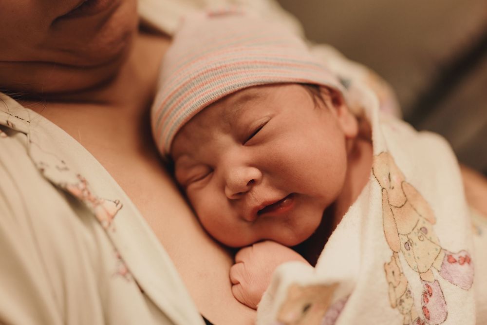 A swaddled baby rests with a gentle smile while wrapped in soft blankets.