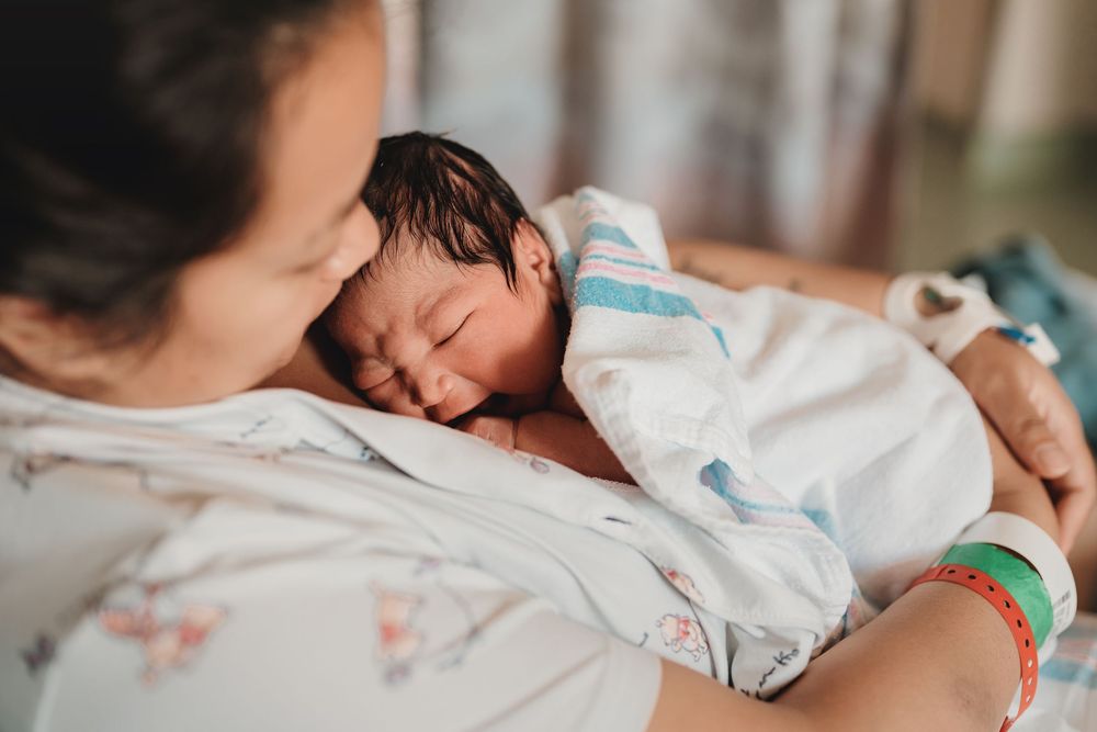 A mother shares a tender moment with her newborn baby in the hospital bed.