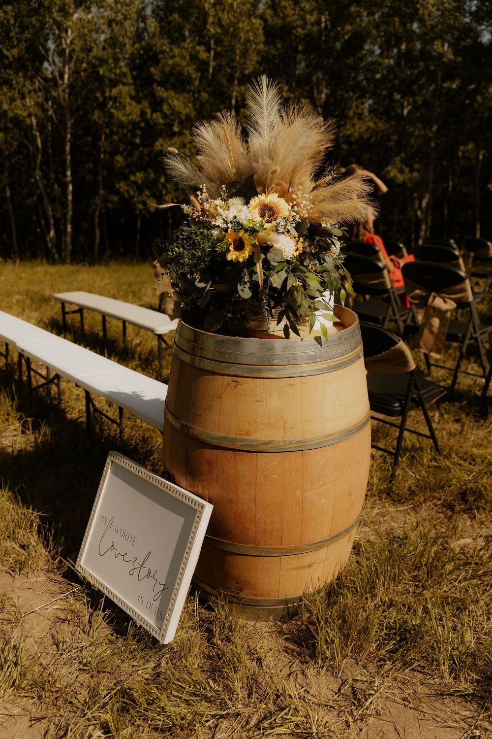 Rustic wedding decorations featuring wine barrels with sunflower arrangements and signage.