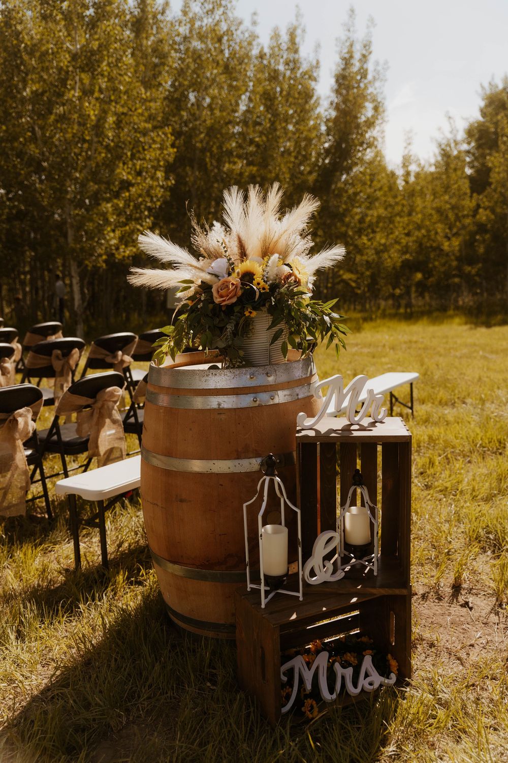 Outdoor wedding ceremony setup with wine barrels, floral arrangements and Mr & Mrs signs.