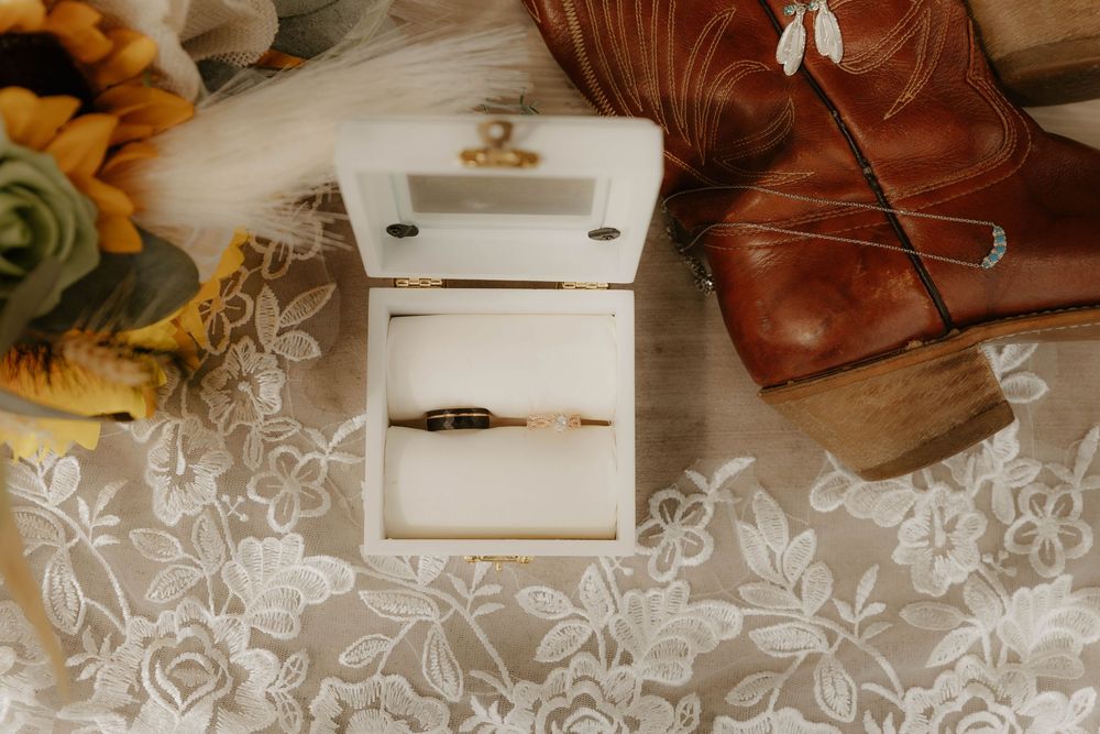 Rustic wedding decor with lace curtains, cowboy boots, and floral arrangements.