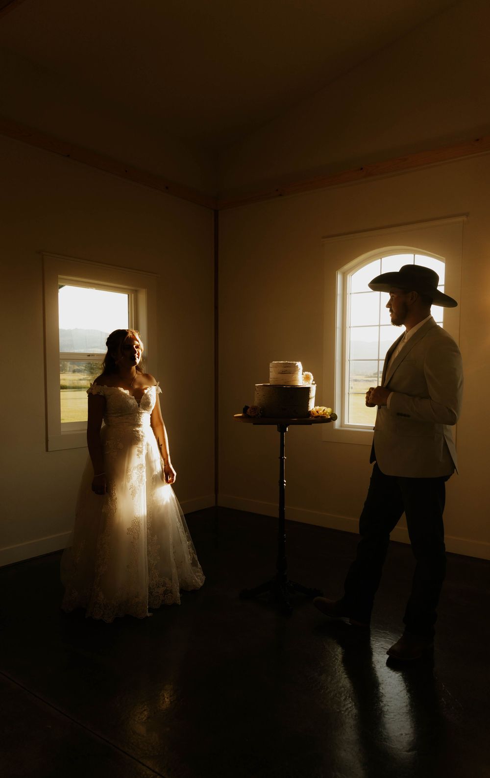 Silhouettes of western wedding preparations against backlit windows in a dim room.