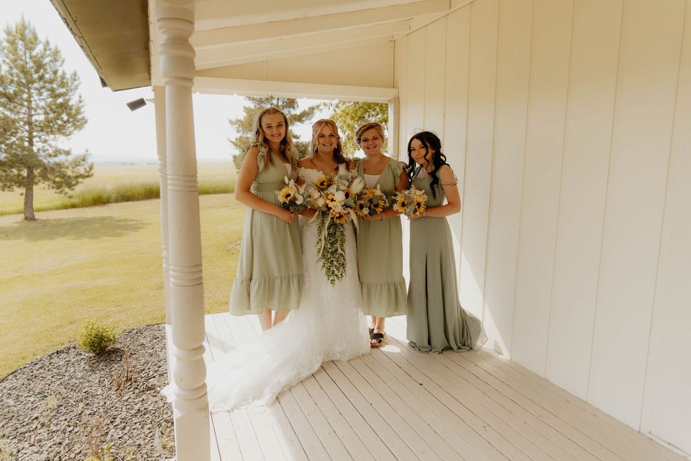 Soft-focused image of a wedding party standing on a white porch with decorative columns.