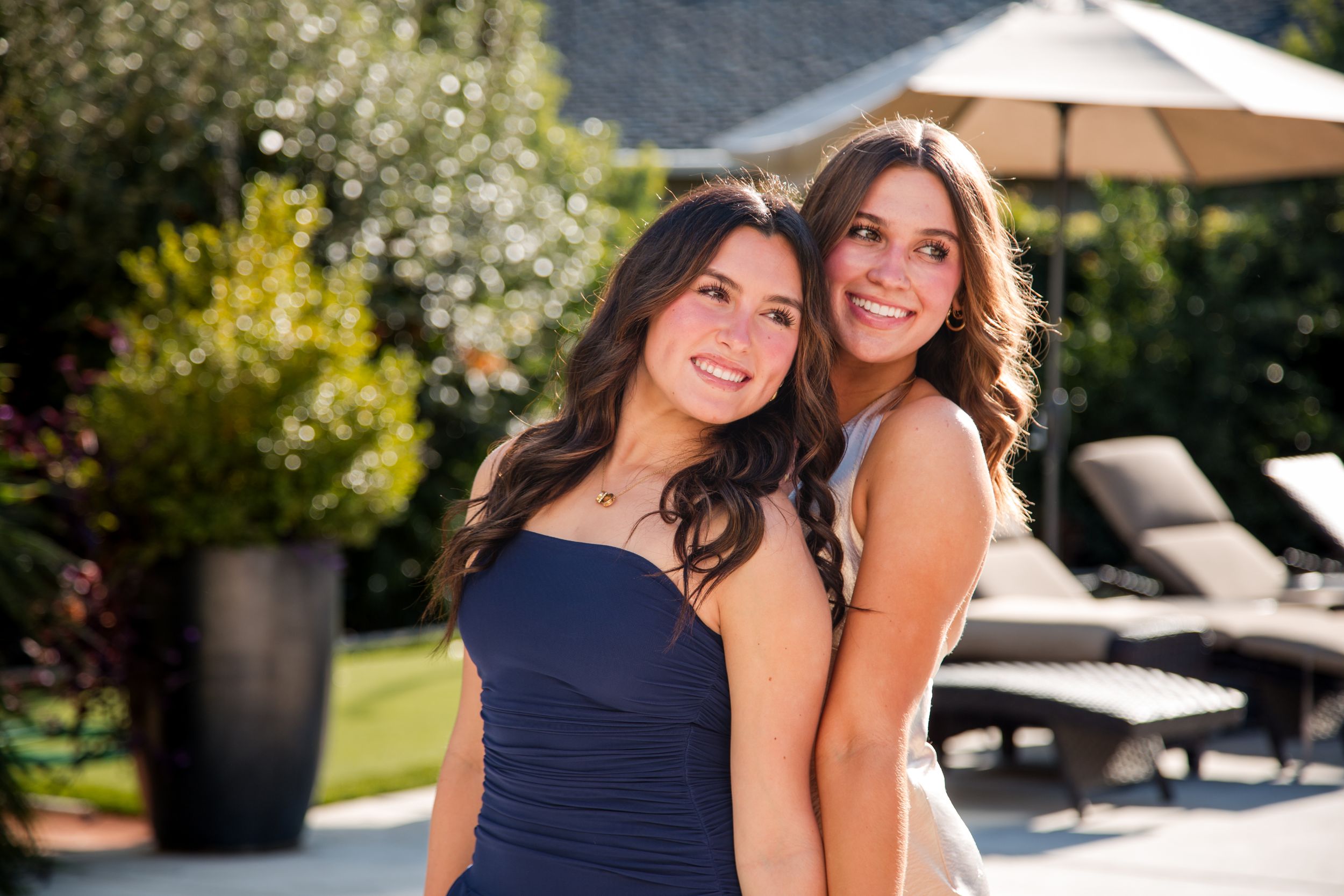 Two women in navy blue and gold dresses pose together outdoors on a sunny day. homecoming photos sacramento california