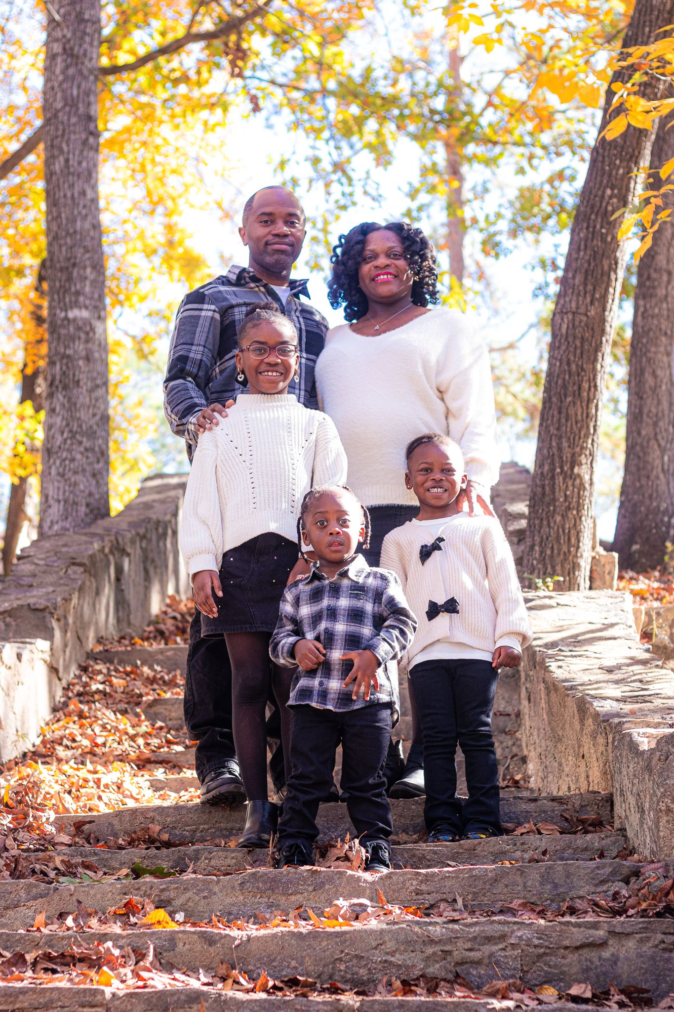 Family of five poses on autumn stone steps surrounded by fall foliage and colorful leaves.