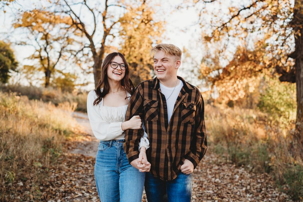 A joyful outdoor couples photoshoot with golden fall foliage in the background.