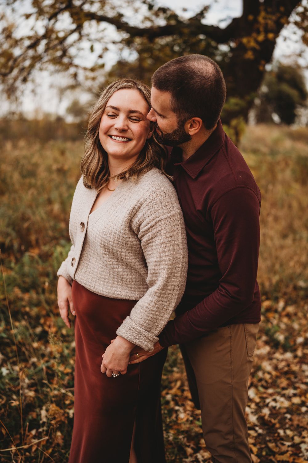 A couple shares loving moments during a fall photoshoot among fallen leaves.