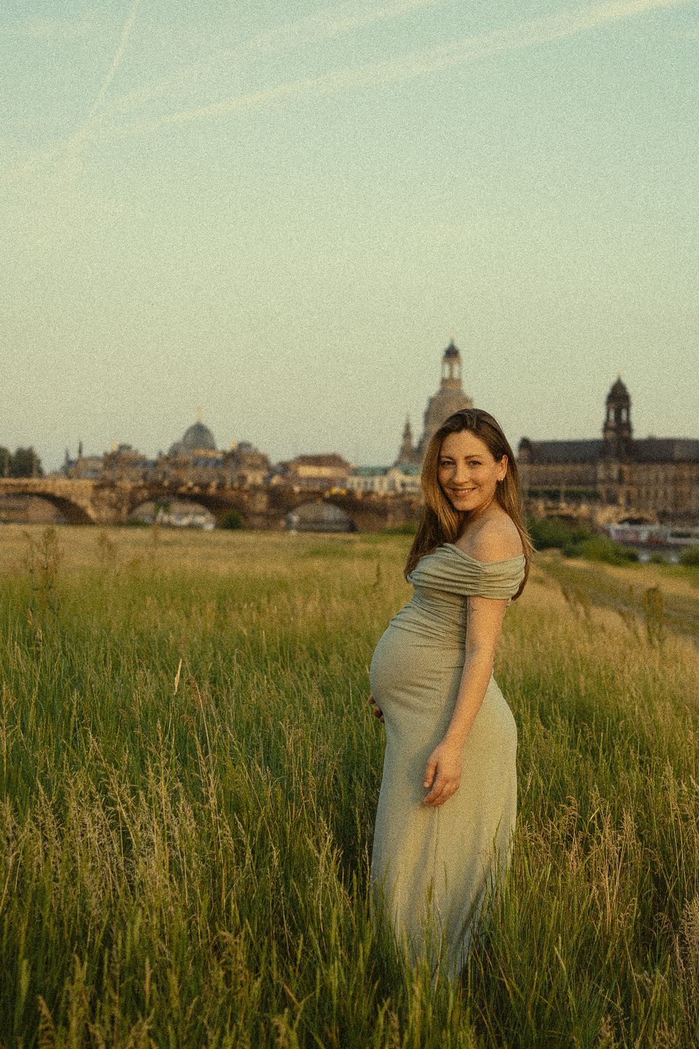 Frau läuft durch hohe Gräser während der Abenddämmerung -  Babybauchfotoshooting Elbwiesen Altstadt Dresden