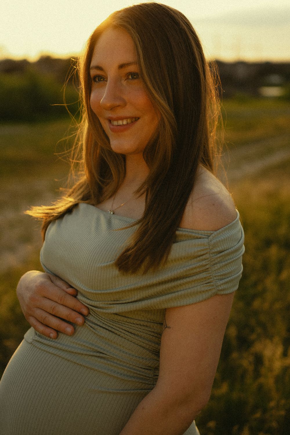 Abendsonne am Himmel leuchtet auf schwangeren Bauch einer Frau - Portrait Fotoshooting Elbwiesen in Dresden