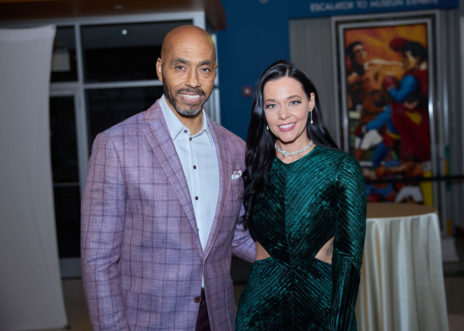 Elegant couple poses in formal wear at indoor event.