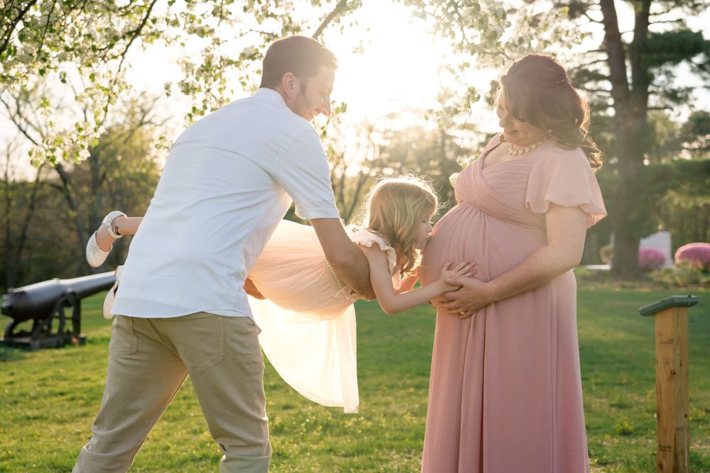 Family enjoys playful moment together in sunlit garden setting.