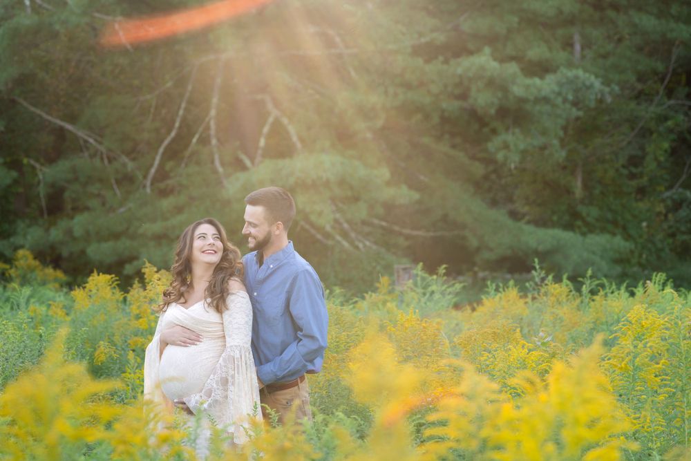 A couple shares an intimate moment in a field of golden wildflowers at sunset.