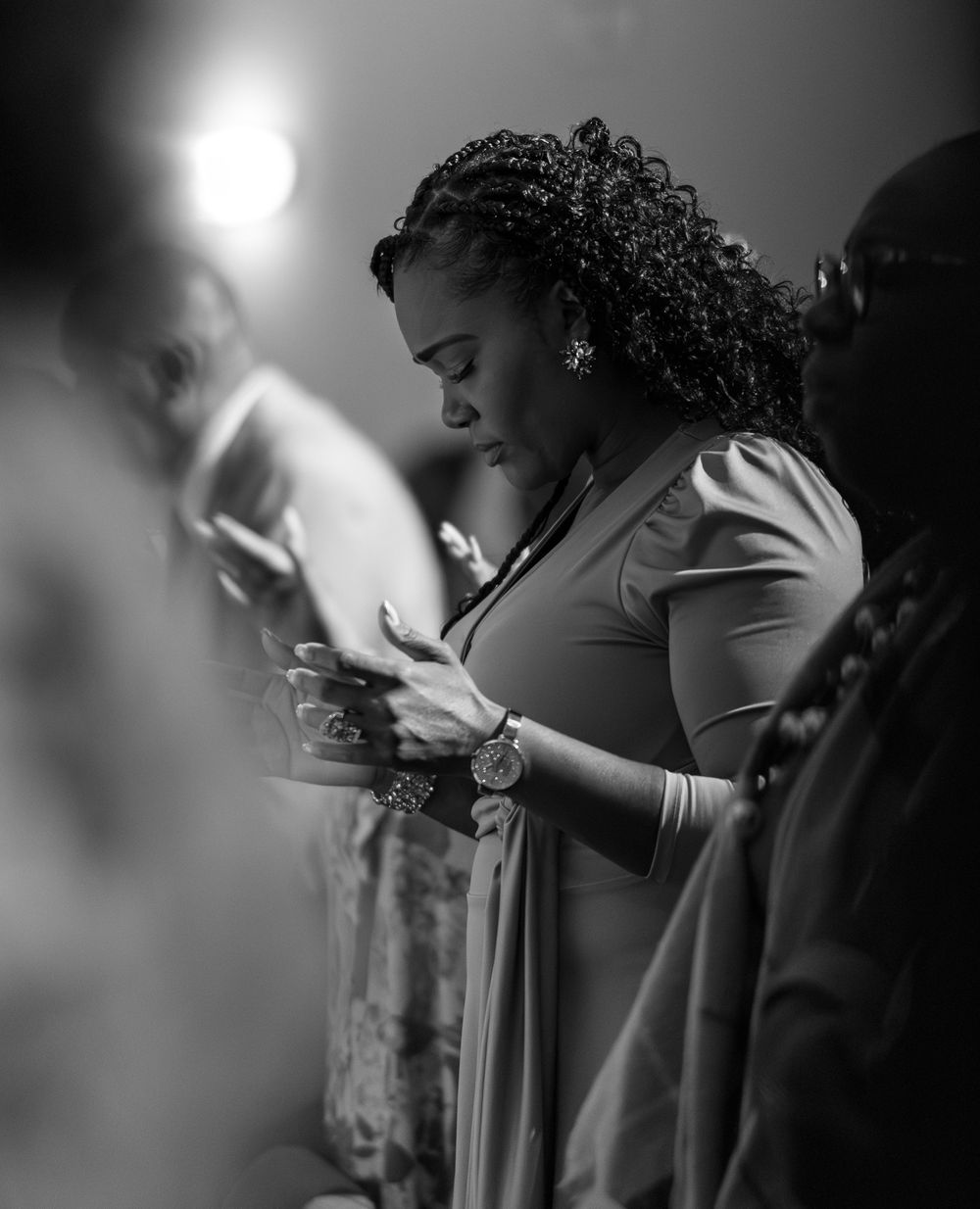 A person in a light colored dress checks their phone in dramatic black and white lighting.