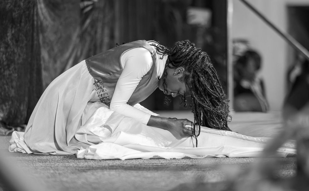 A person kneels in prayer on the ground, captured in black and white photography.