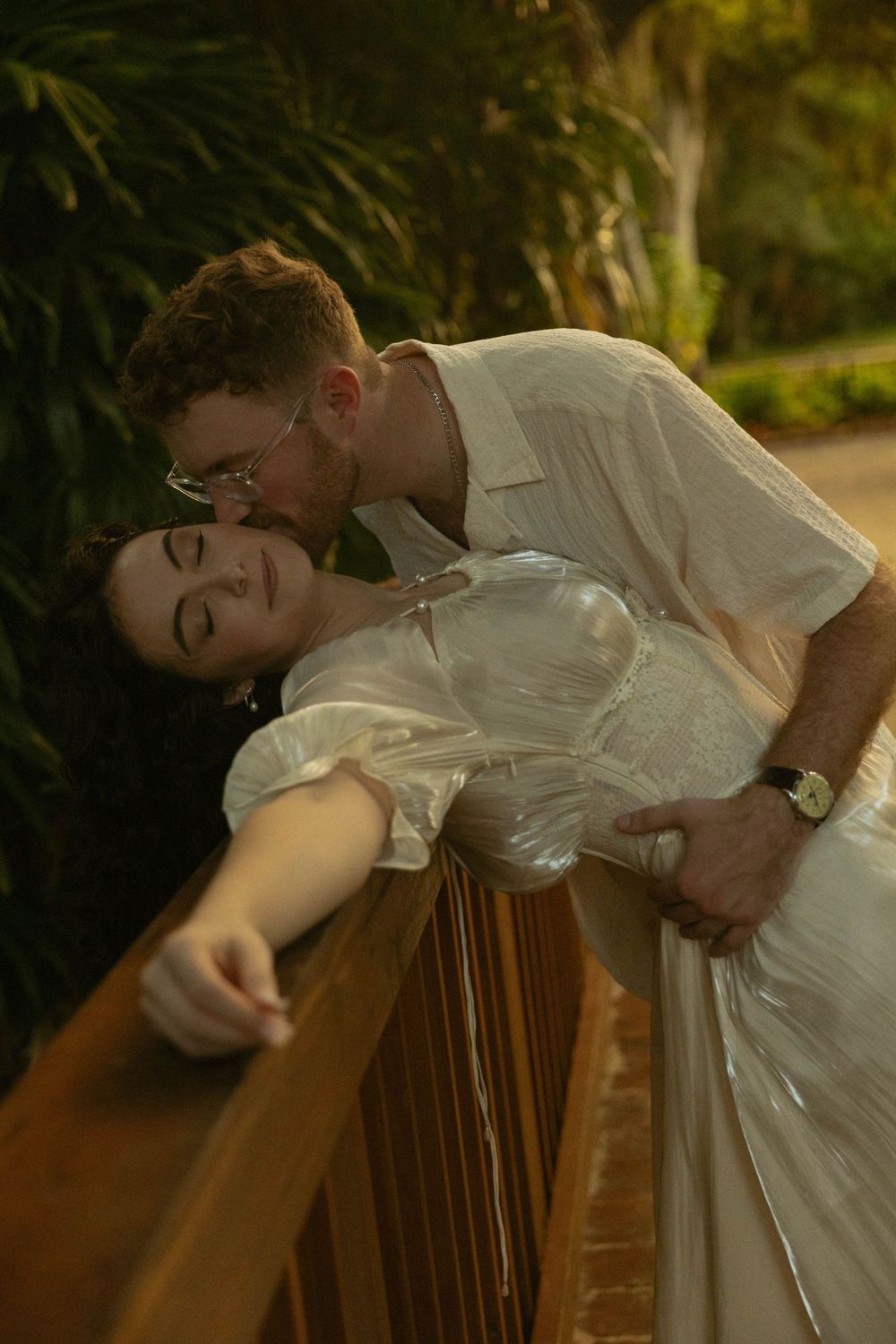 Couple in romantic close-up, woman with engagement ring tenderly touching mans face outdoors.