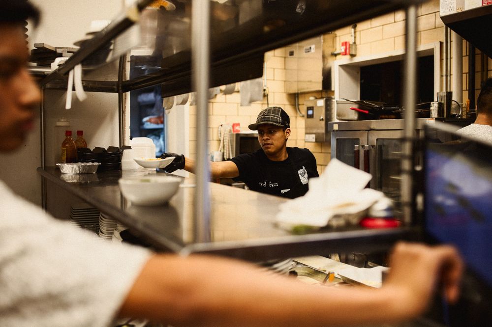Kitchen staff working behind counter in busy restaurant kitchen.