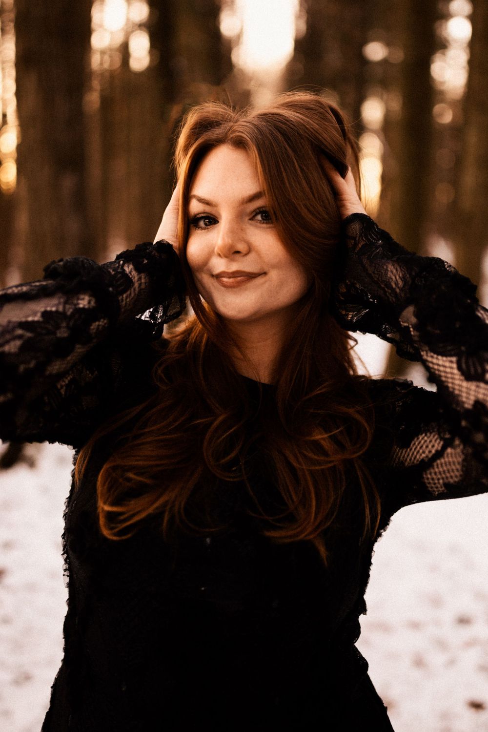Winter portrait featuring black lace sleeves against snowy forest backdrop.