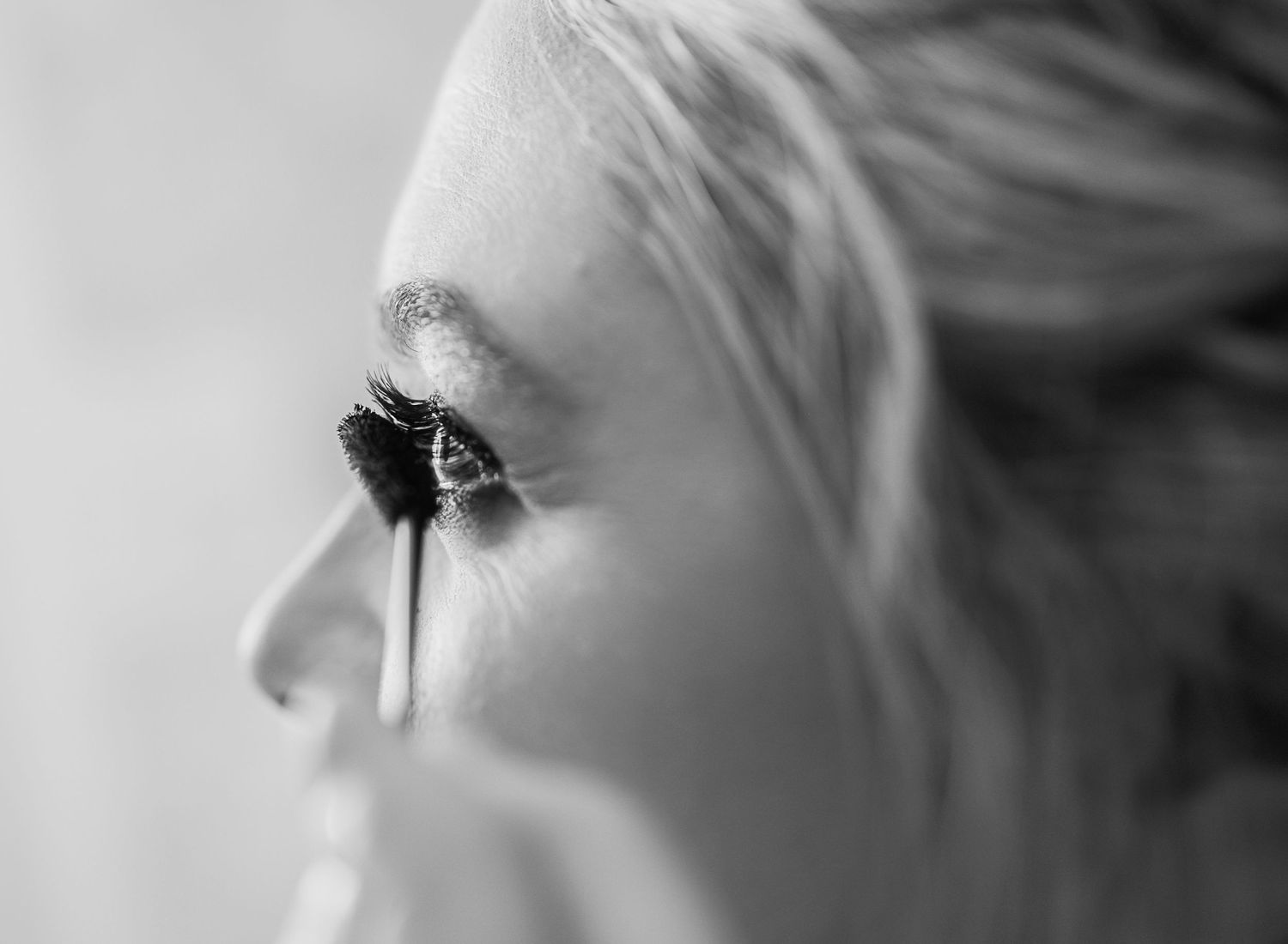 Dramatic black and white close-up profile shot showing long eyelashes and light hair.