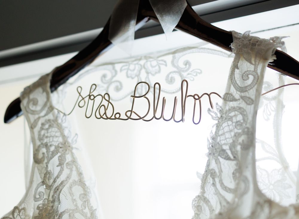 Wedding dress hanging on personalized wire hanger with delicate lace details.