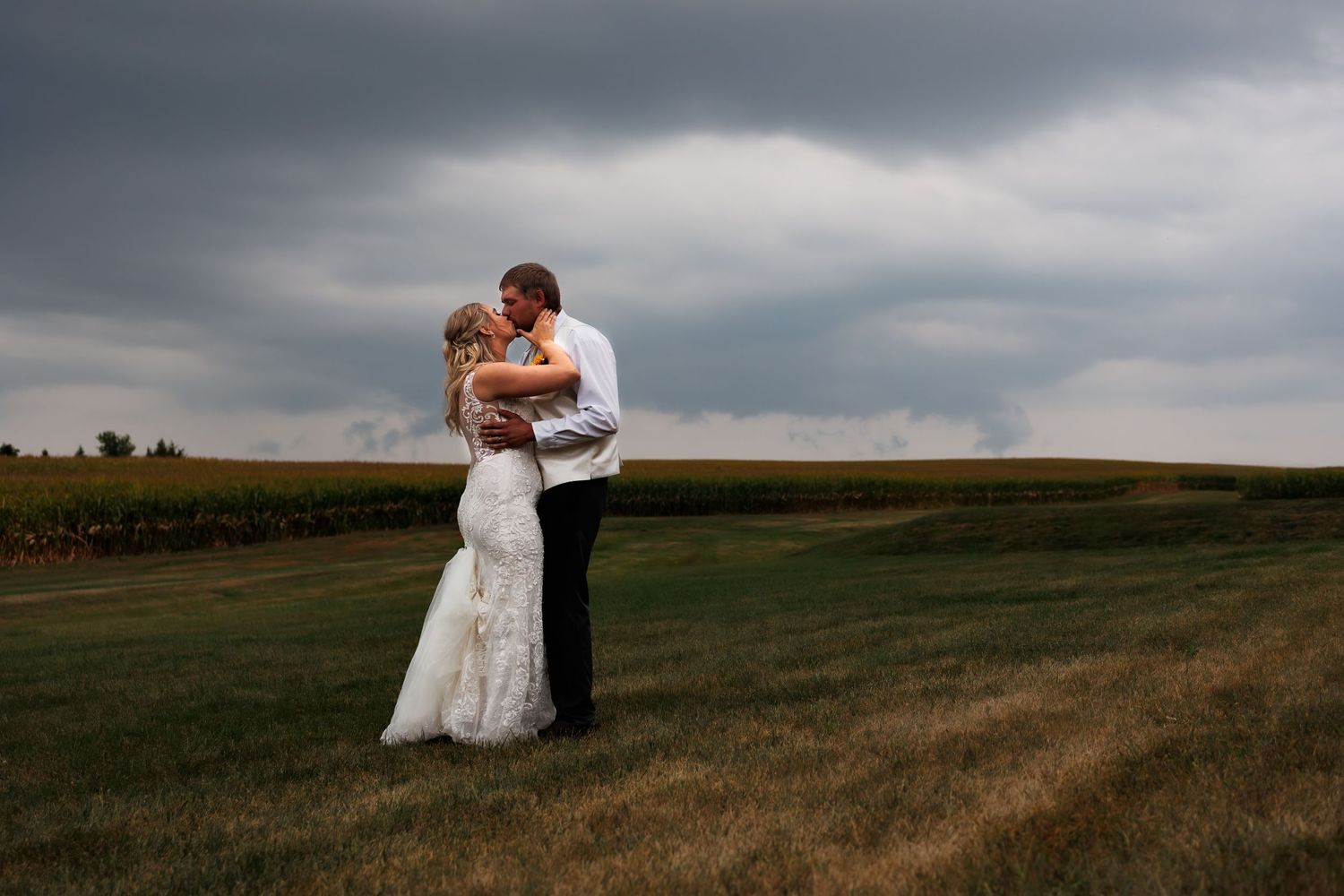 Dramatic wedding portrait against stormy sky in an open field.