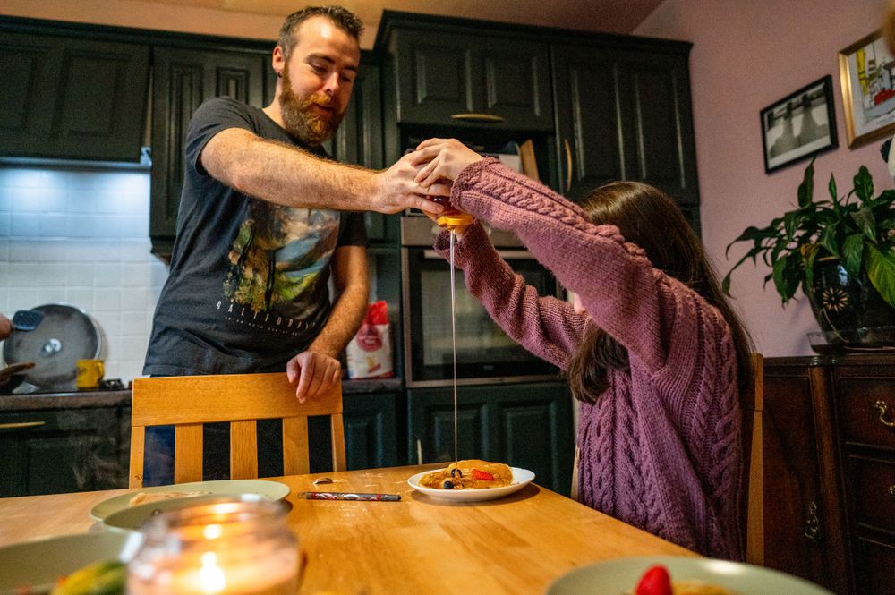 Two people engaged in playful tug of war over food at dining table.