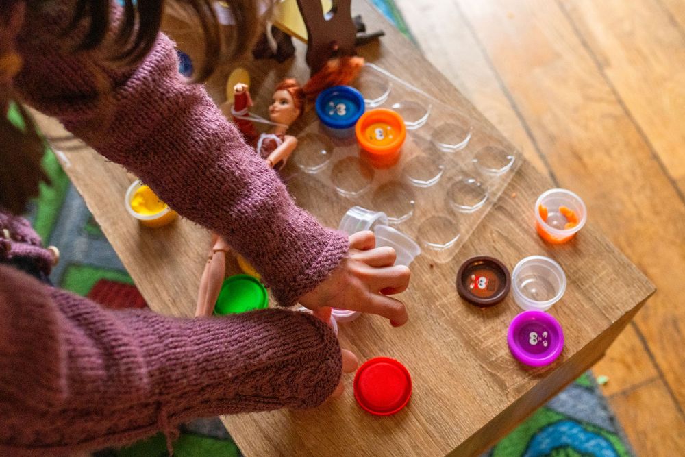 Hands playing with colorful game pieces on wooden floor.