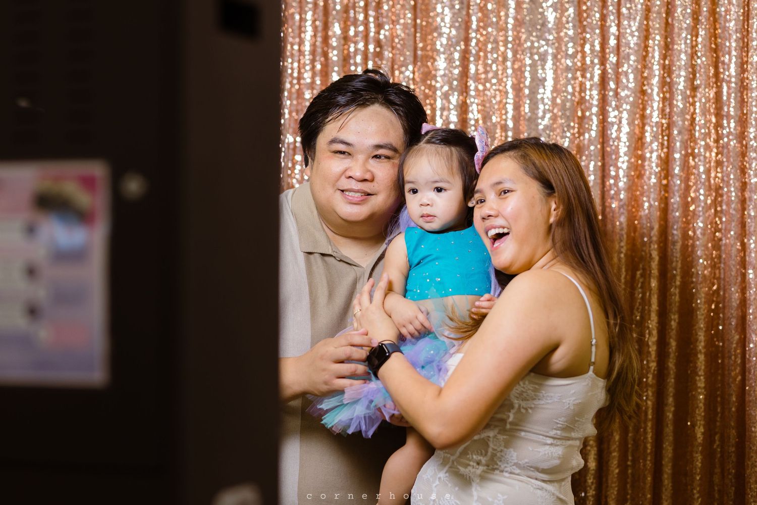 A family shares a joyful moment together in front of a sparkly gold sequin backdrop.
