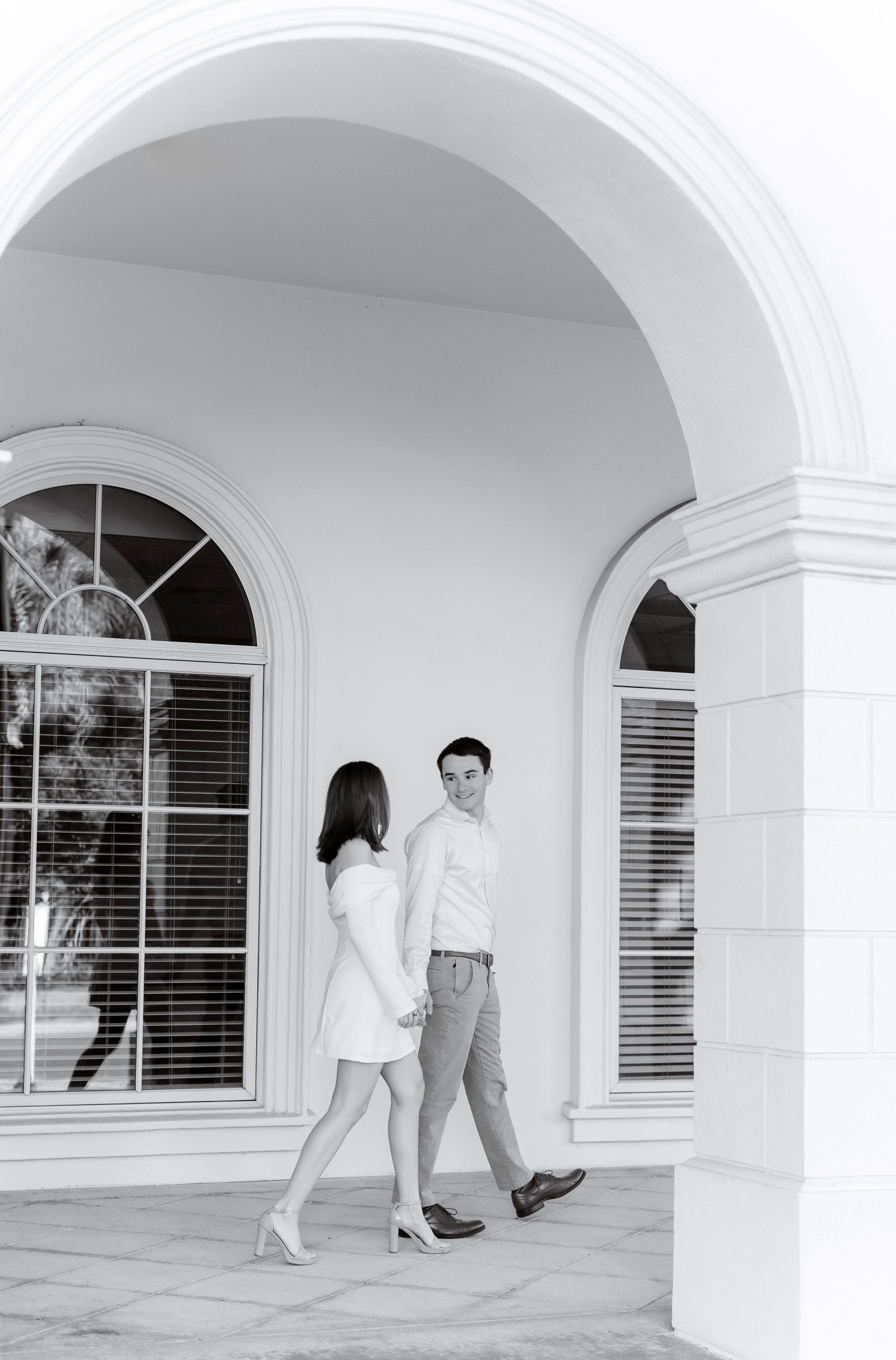 Black and white photo showing a series of elegant white arches with windows and architectural details.