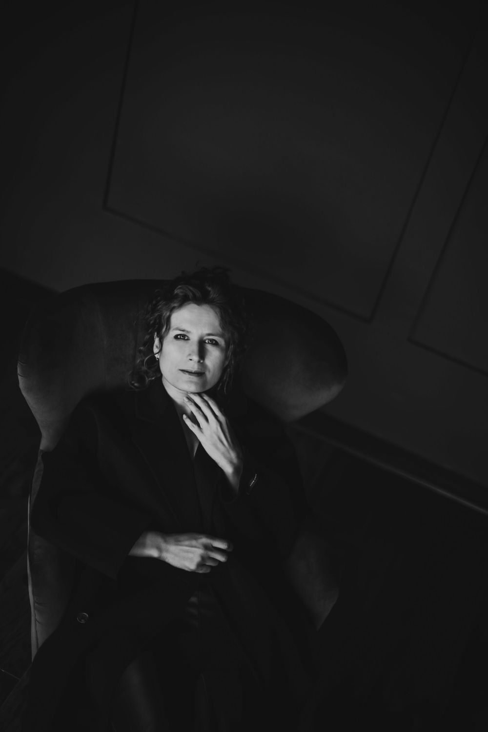 Artistic black and white photograph of person reclining on dark couch. Bellevue studio, WA