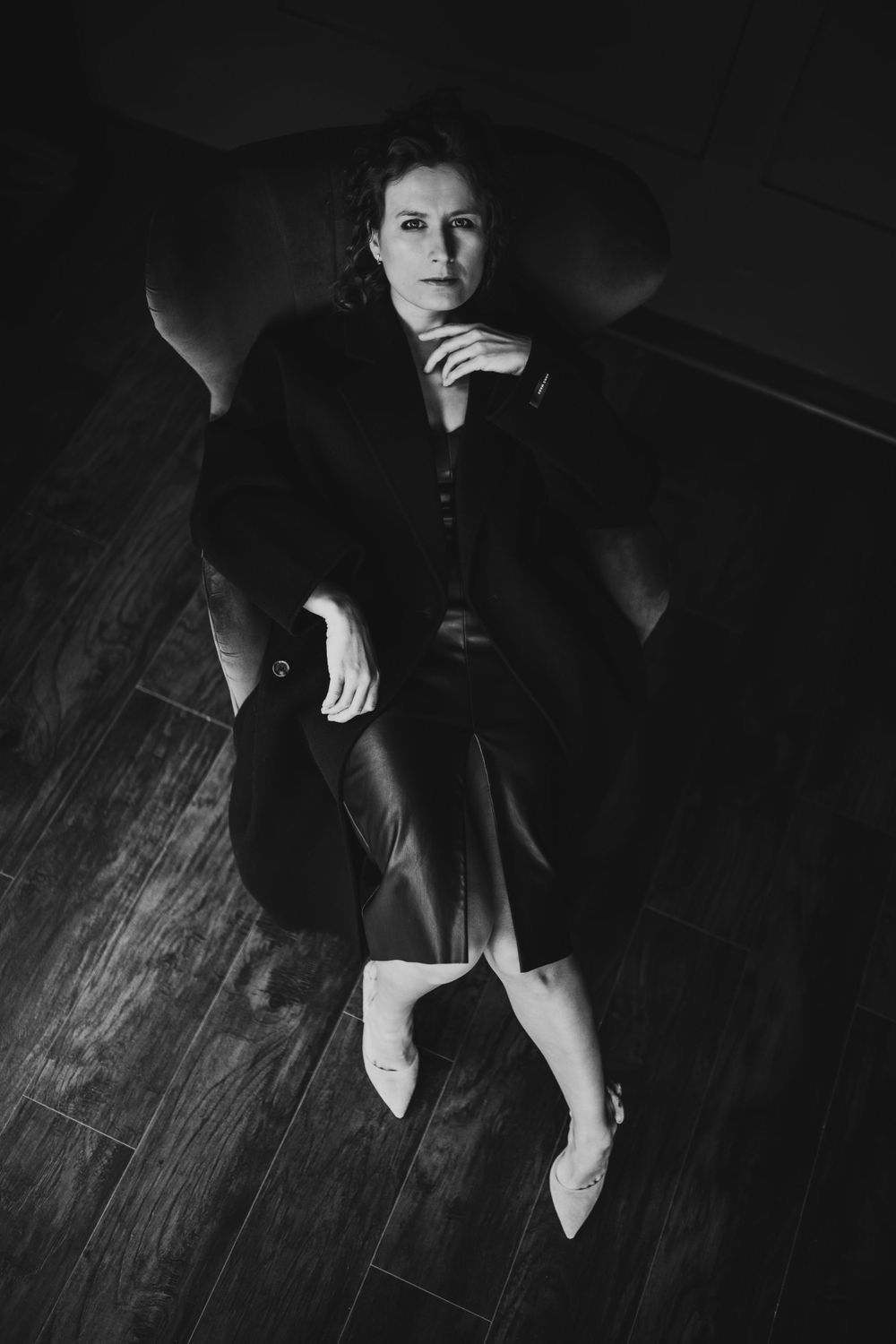 High contrast monochrome portrait of figure seated on couch wearing formal attire. Bellevue studio, WA