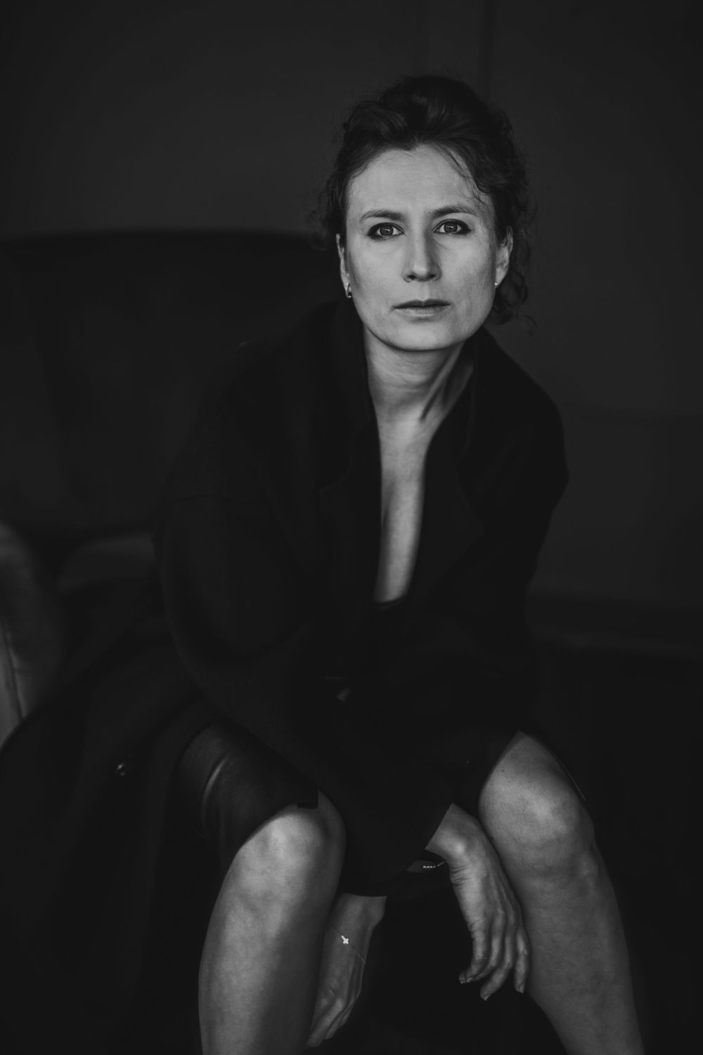 Sophisticated studio portrait in black jacket seated against dark background. Bellevue studio, WA