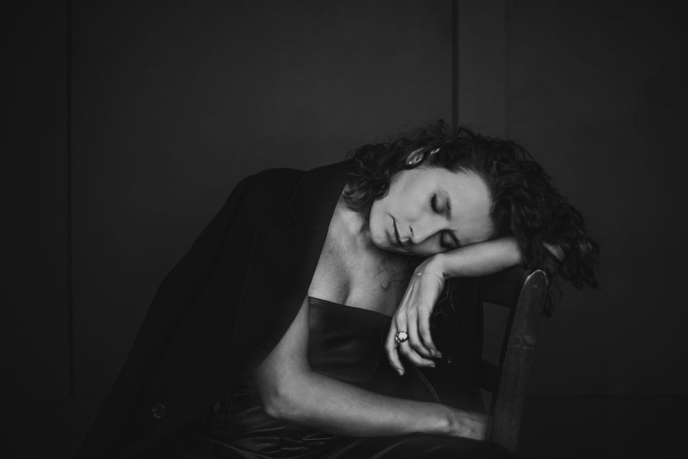 Atmospheric black and white photo of figure resting head on surface in contemplative pose. Bellevue studio, WA