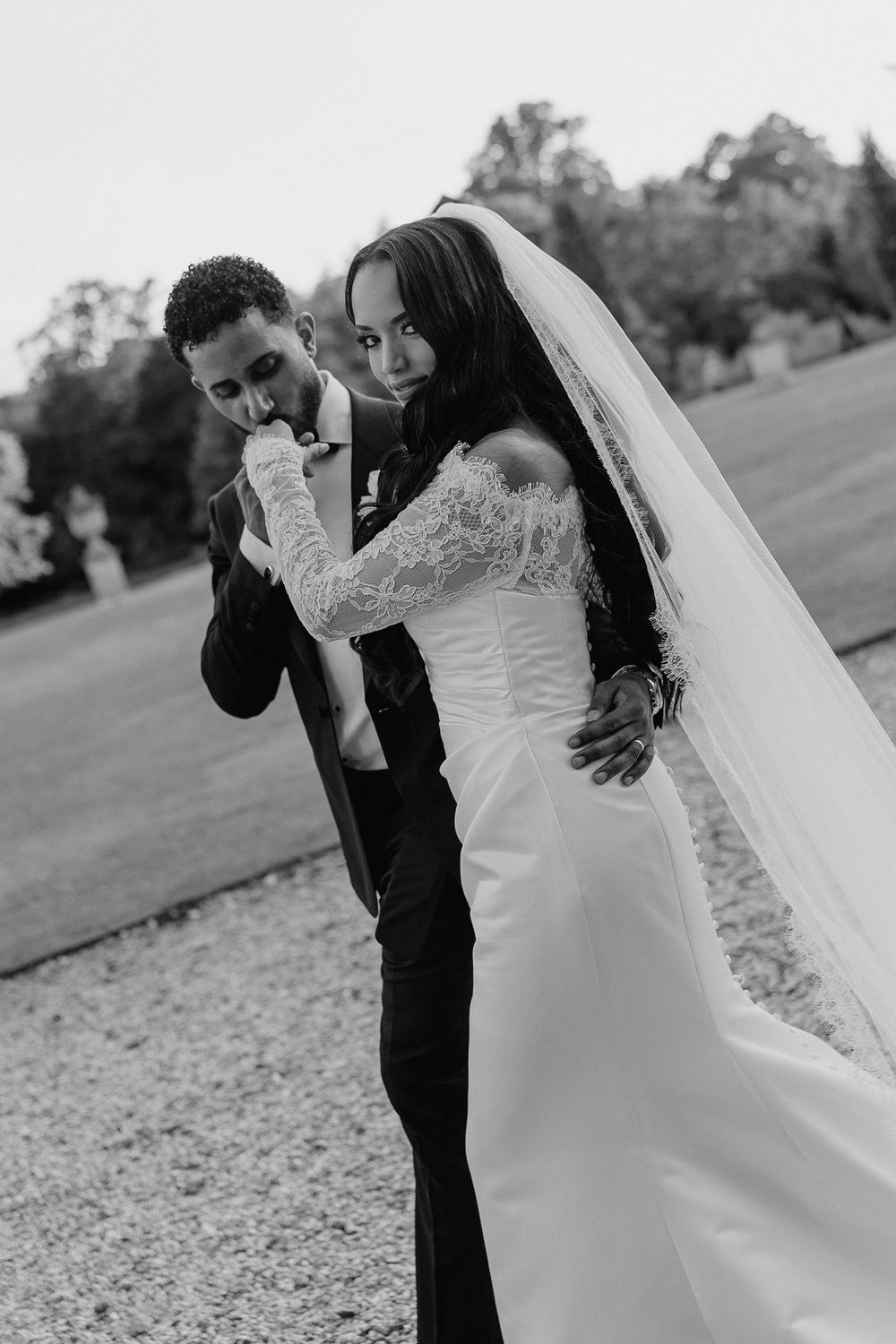A romantic moment between newlyweds outdoors as the groom kisses the bride's hand.