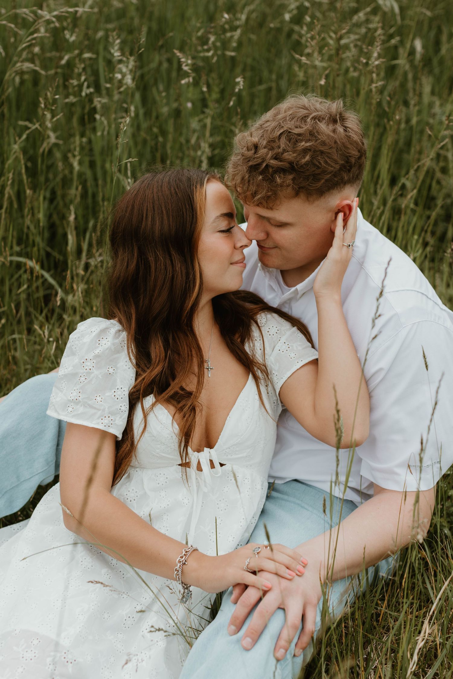 Intimate couples photoshoot in tall grass showing romantic poses and tender moments.