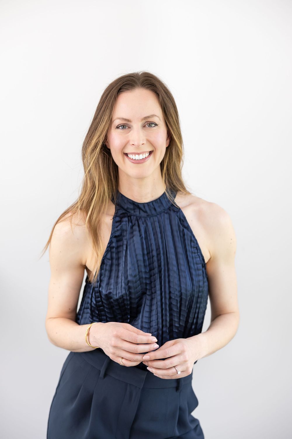 Jessica Stegner Seattle, WA based SEO strategist for small travel businesses headshot standing posed lightly holding hands in blue outfit