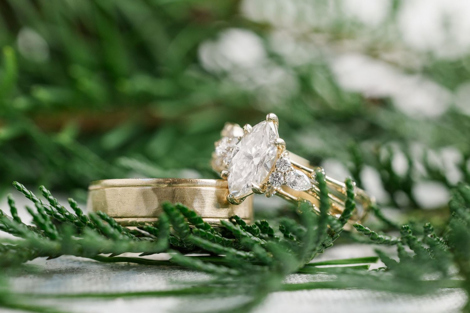 Wedding rings with diamonds displayed with colorful flowers on white surface.