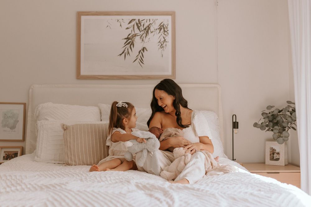 Mum breastfeeding with toddler on bed
