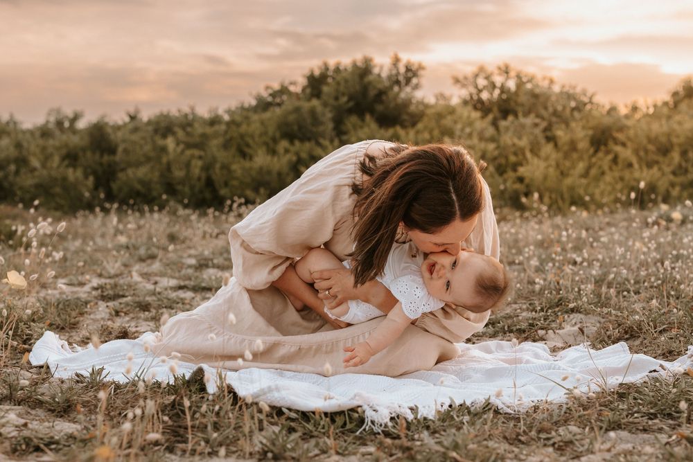 Mum kissing toddler at sunset