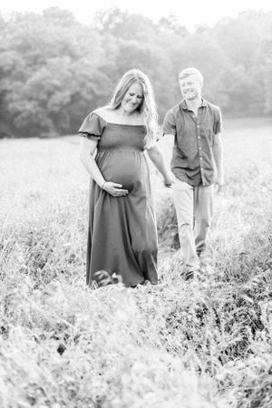 A couple stands in a meadow during a maternity photoshoot in Springfield, MO.